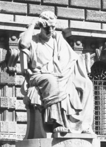 A classical Roman sculpture of a man in contemplative seated pose.